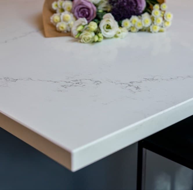 Close-up of a white veined worktop edge with flowers